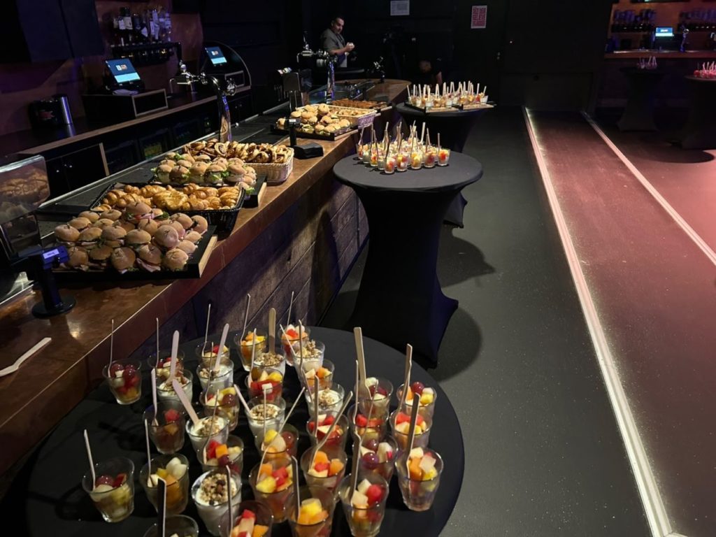 Het ontbijtbuffet van De Oude Keuken bij het Miljoenenontbijt in Poppodium Victorie, met bekertjes fruit vooraan en de zaal erachter